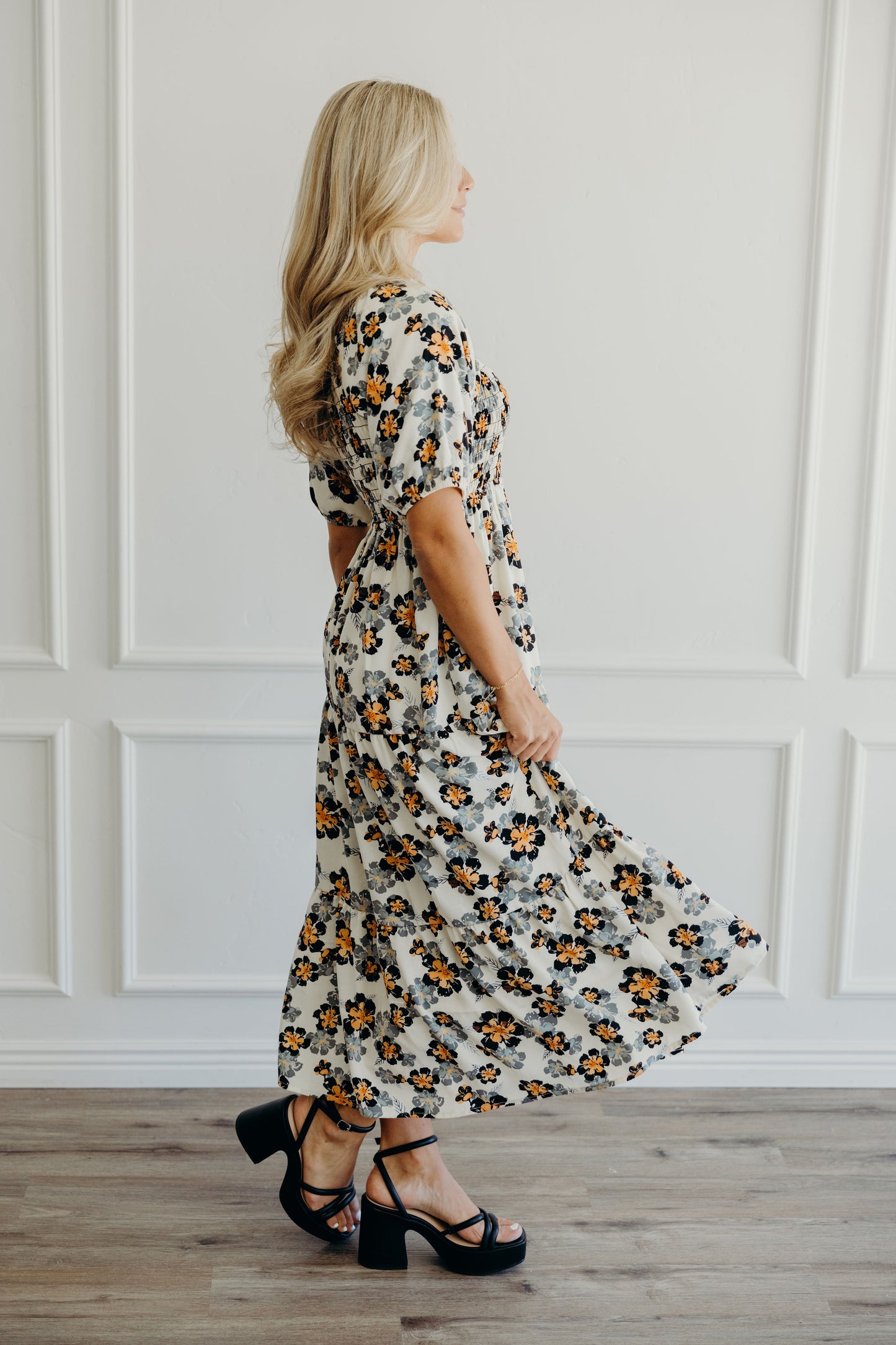 Side view of cream print dress with black and orange flowers, and half sleeve with elastic cuff.