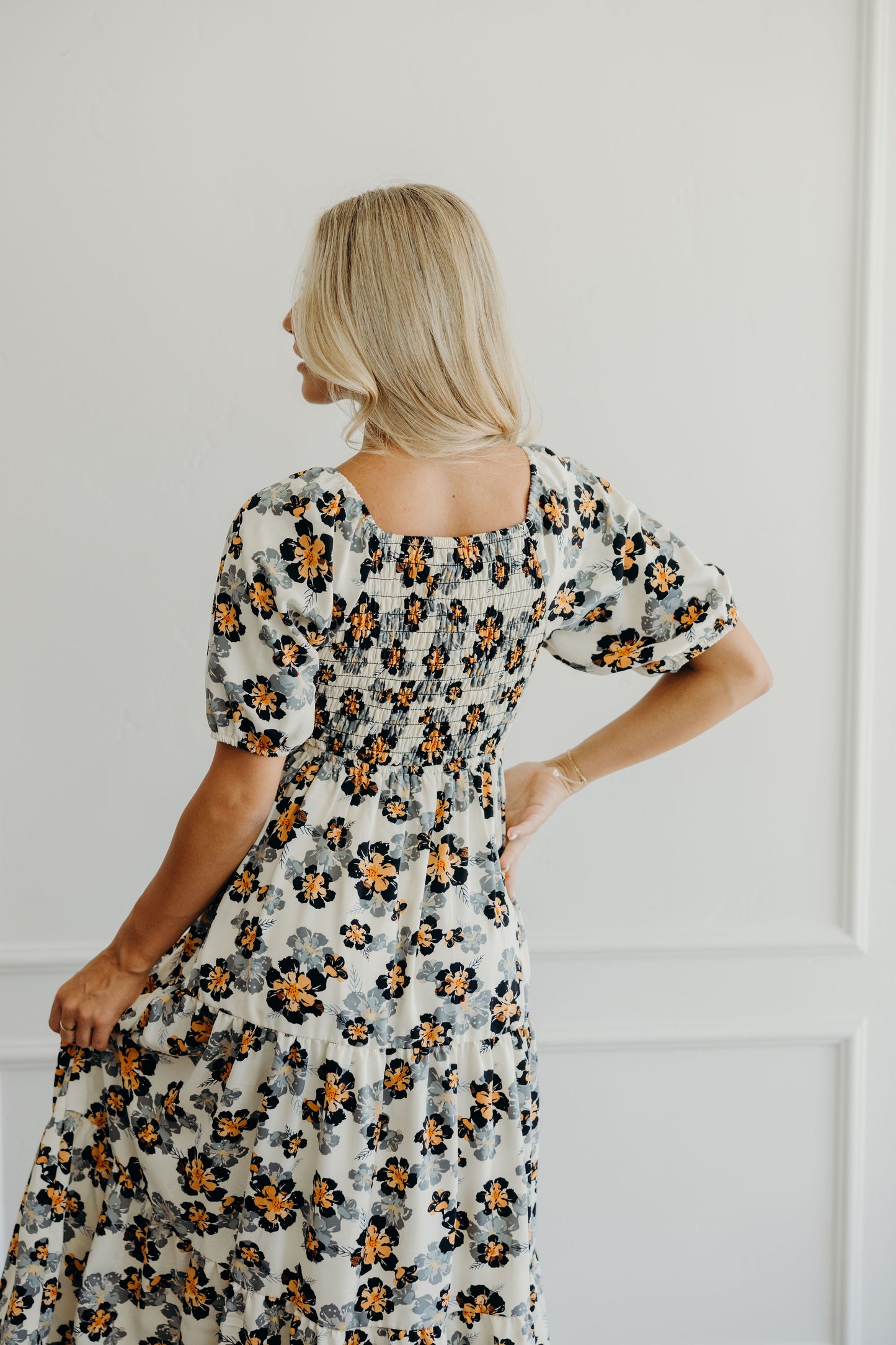 Back view of cream floral print dress with smocking on back and half sleeves.