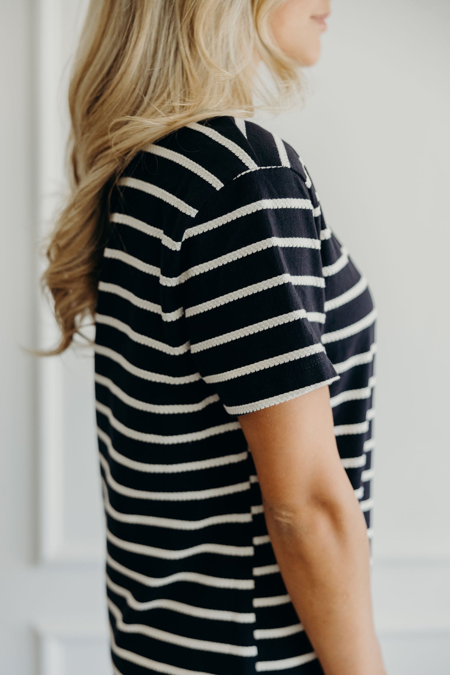 Detail shot of black t shirt styled dress with cream textured stripe.