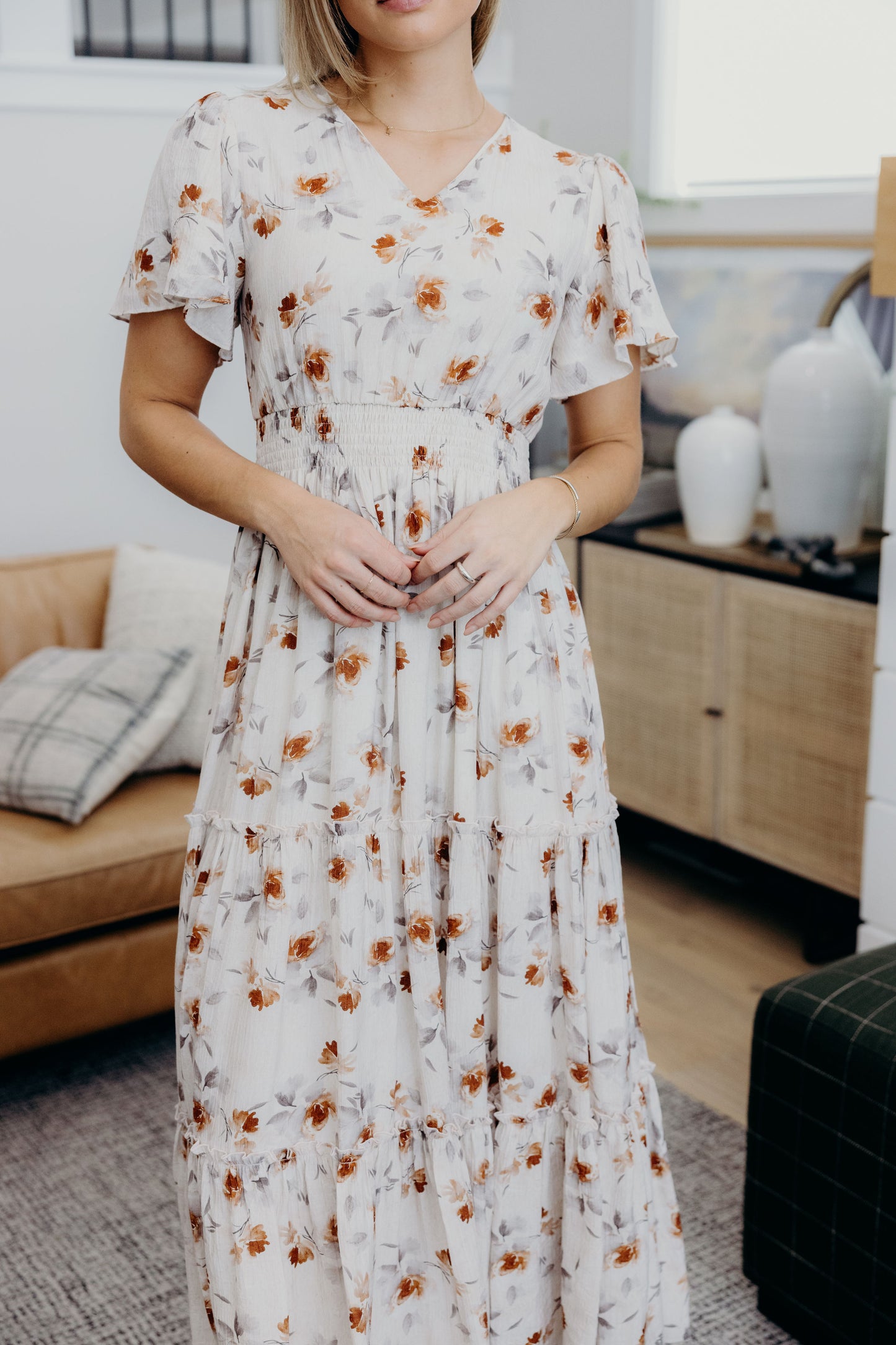 Cream print dress with smocked waist, tiered skirt, and flutter sleeves.