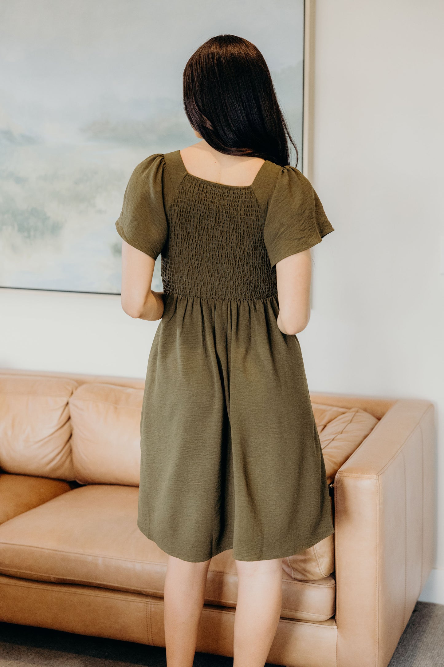 Back view of knee length dress with short sleeves and smocked bodice.