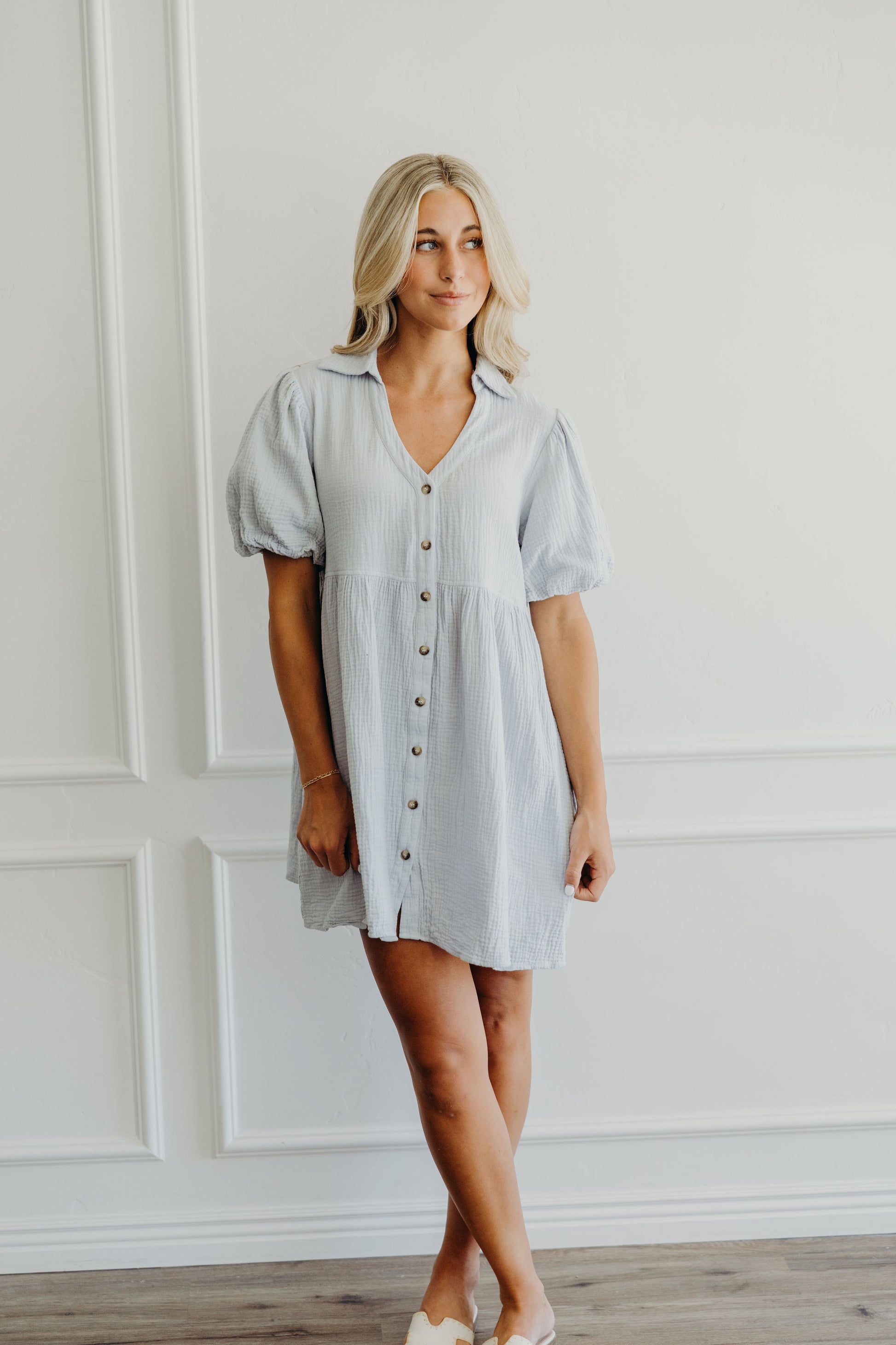 Short light blue dress with natural waistline, v neckline, puff sleeves, button down and collar details.