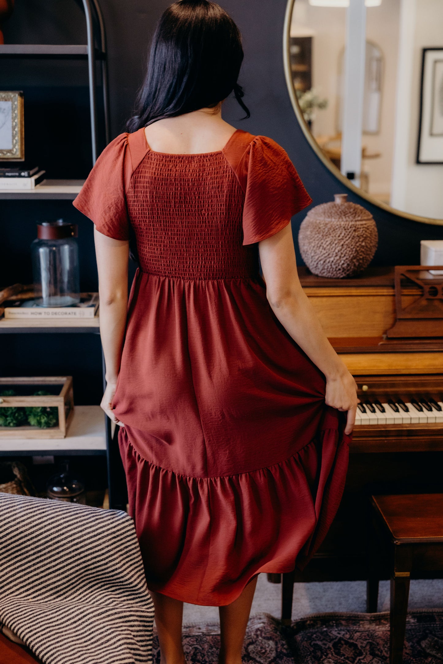 Back view of dark red dress with smocked bodice, natural waistline, and ruffle hem.