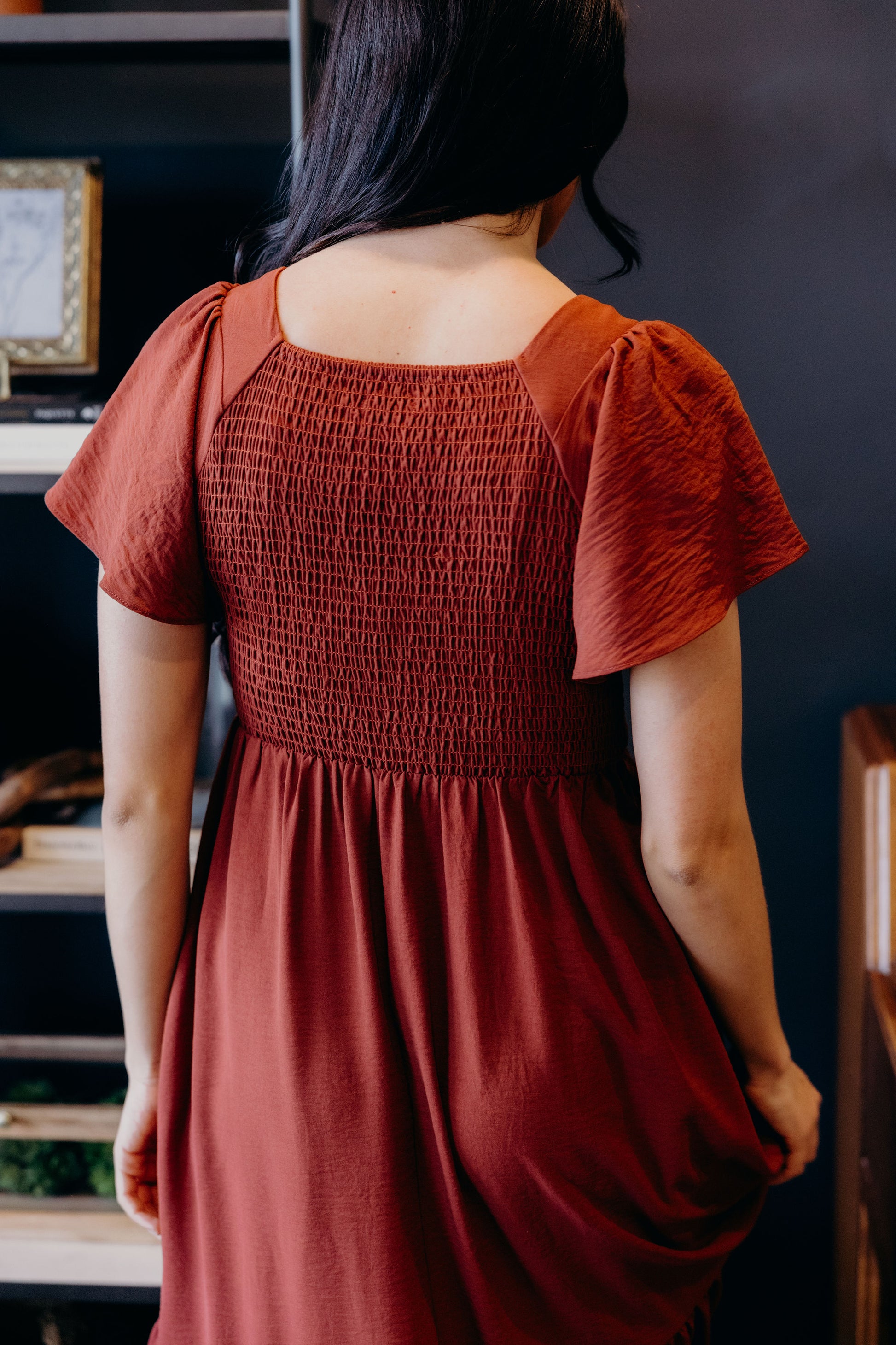 Back view of dark red dress with flutter sleeves, and smocked bodice.